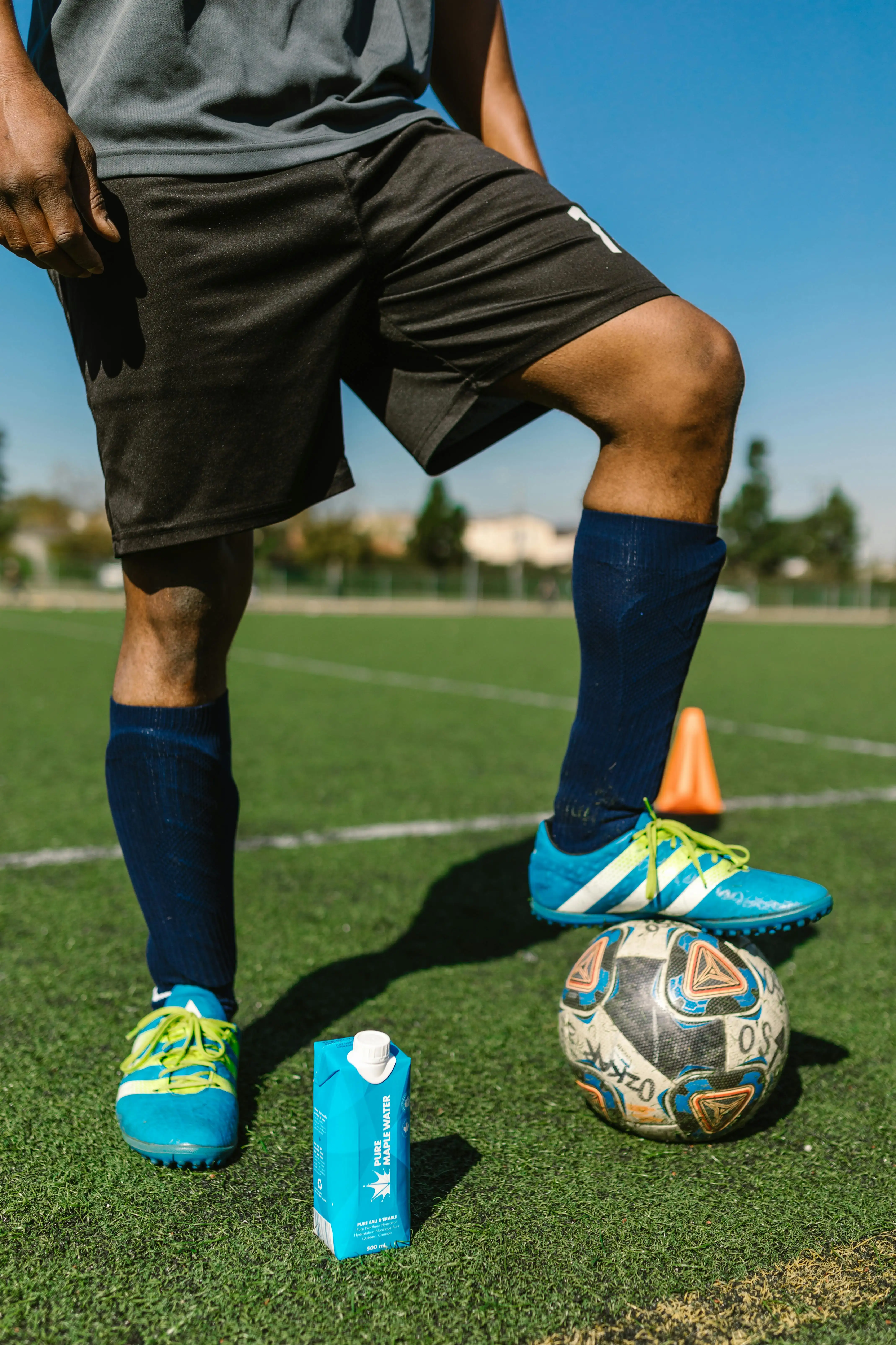 Cancha de fútbol bajo techo, conos de agilidad, pelotas y material de entrenamiento, luz natural, sin personas